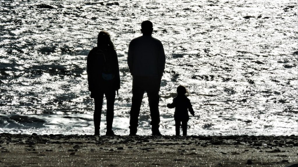3 men standing on seashore during daytime