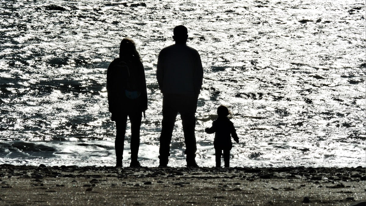 3 men standing on seashore during daytime